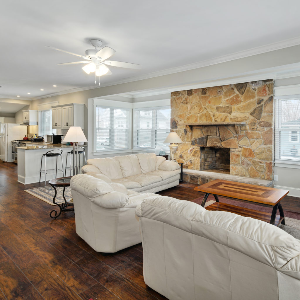 Renovated kitchen and living room space with fireplace and leather seating at Full kitchen stylishly designed with seating and updated appliances at Somerdale Sober Living Homes for Men