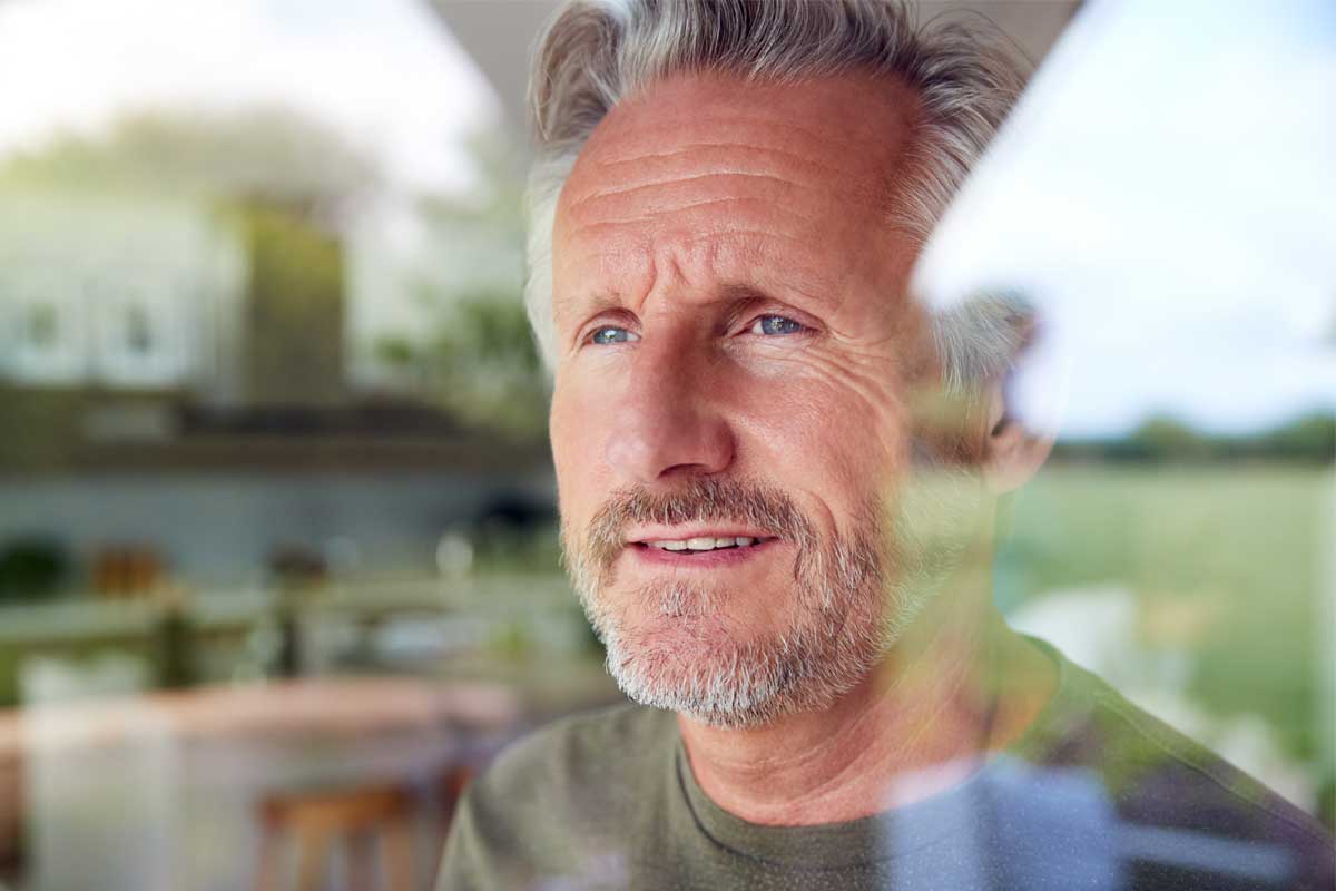 Man looking out window contemplating how to make the most of sober living